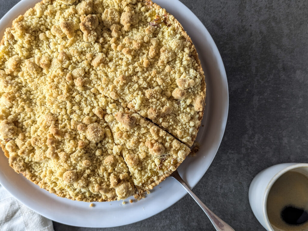 Ganzer Rhabarber Streuselkuchen in der Springform von oben – goldbraune Streusel mit rosa Rhabarberstücken